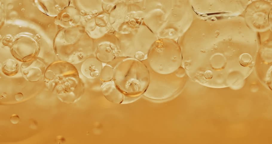 Clear yellow bubbles slowly floating and moving around in liquid