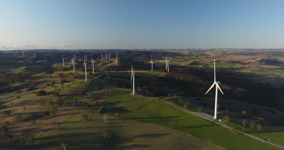 Wind turbines spin on a wind farm under a clear sky