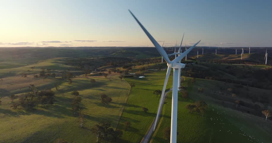 Wind turbines on a field rotating clockwise at sunset
