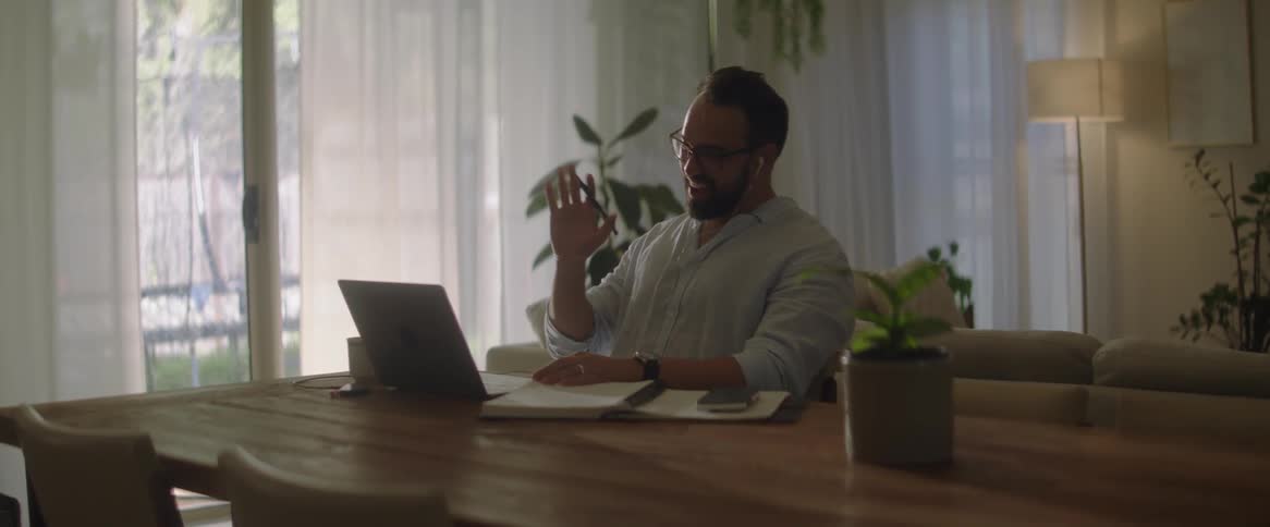 Man working from home talks on a video call through a laptop