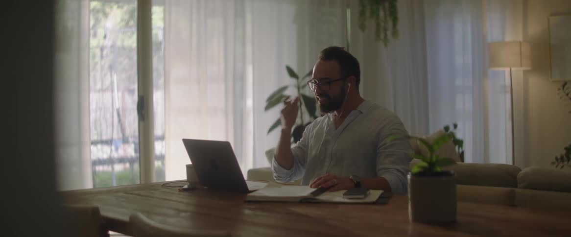 A man is sitting in a meeting with a laptop on the table