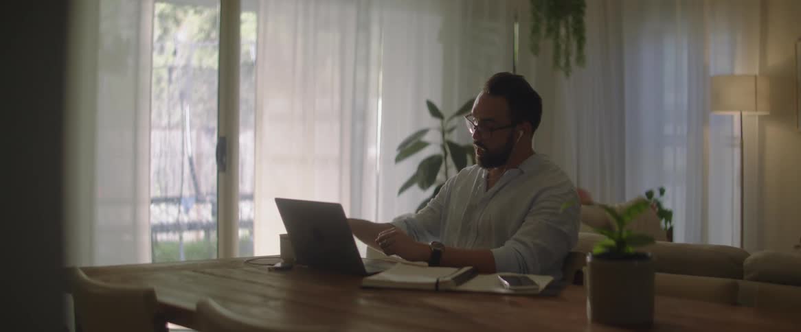 A seated man is talking and gesturing with someone on the computer on the table