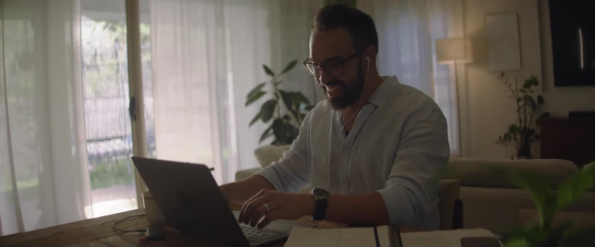 A man is drinking coffee while working on his laptop