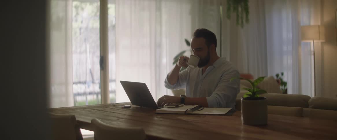 Man working from home drinks a hot beverage