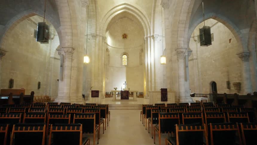 A large church with tall white cathedral ceilings with old architecture and individual chairs in the alter