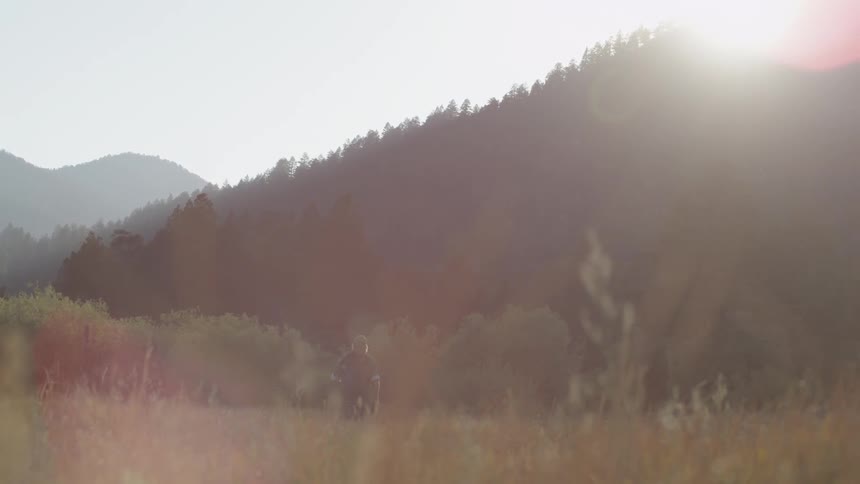 A man is hiking over a field on a sunny day,