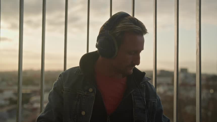 A man puts on large headphones and grabs his smart phone