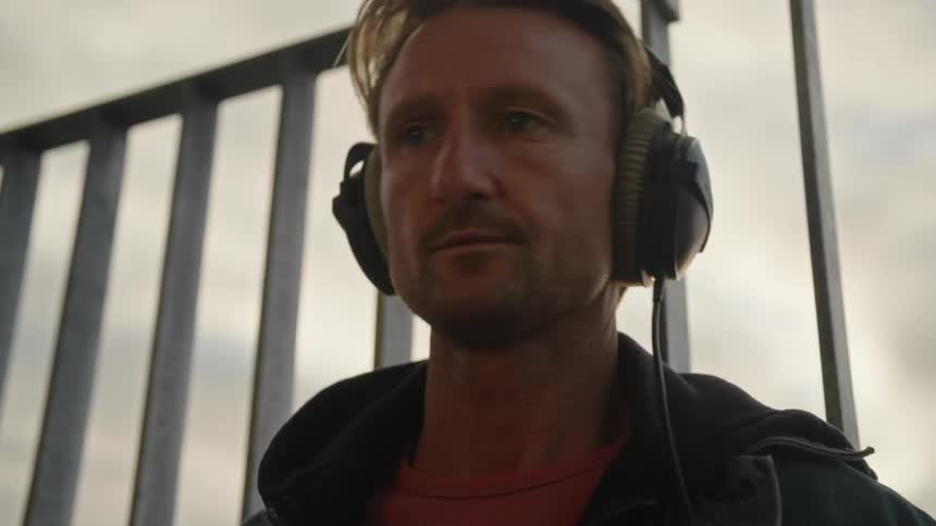 A man has headphones on while he plays the drums