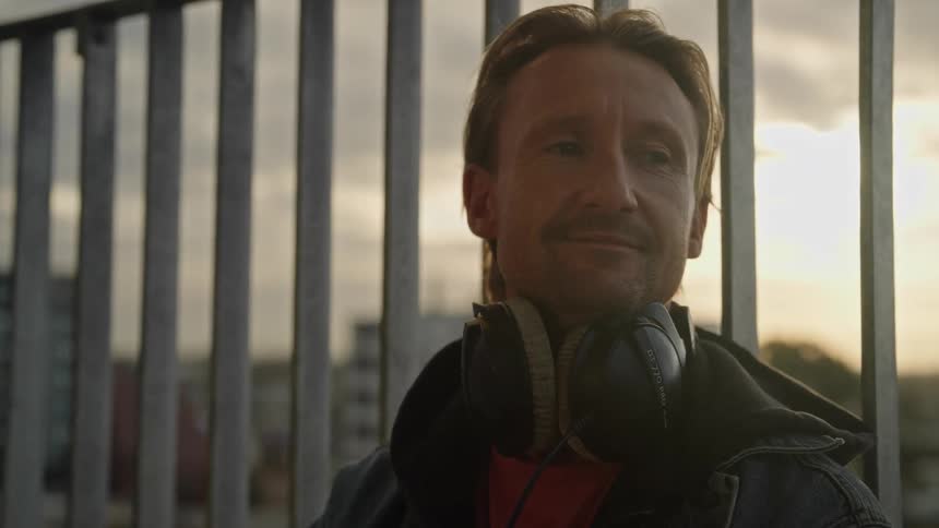 Portrait of a man with headphones around his neck and a happy and sentimental facial expression