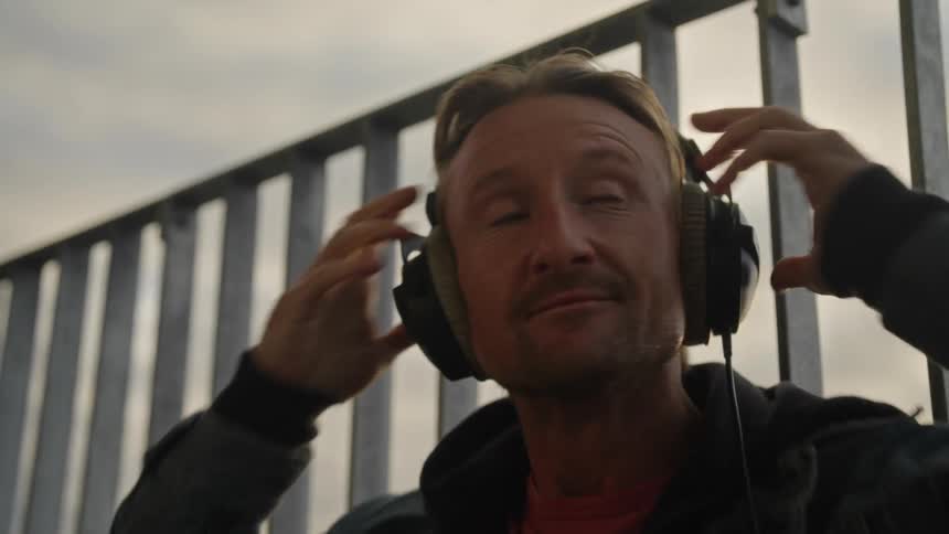 Portrait of a man listening to music excitedly removing his headphones and becoming thoughtful