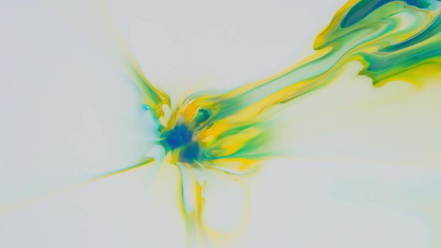 Yellow blue and green paint slowly swirled on a white canvas from the center outward