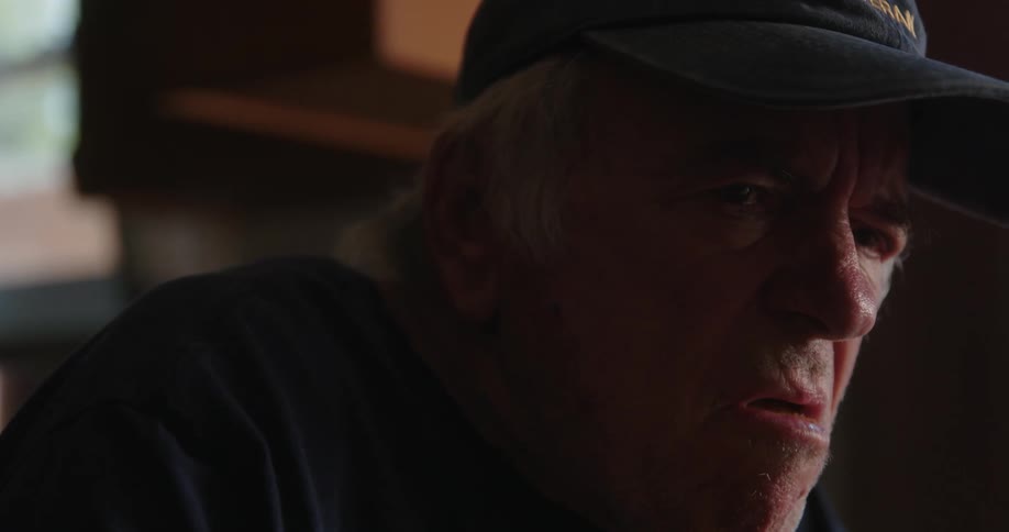 An elderly man takes a bite of an egg roll