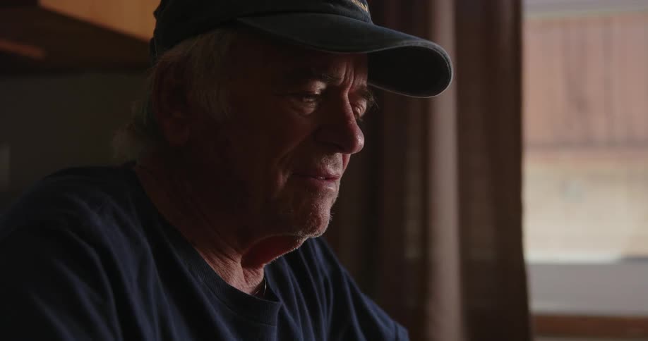 Portrait of an elderly person sitting indoors having a conversation with someone