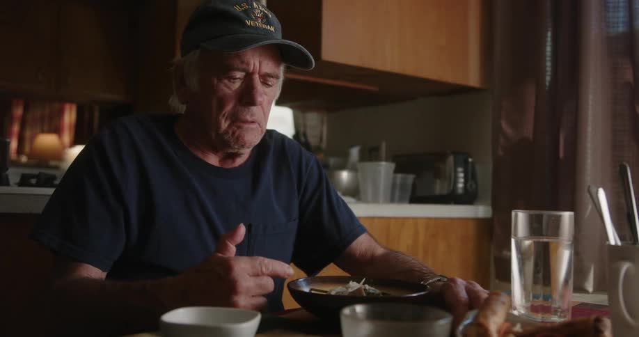 An elderly man contemplating while sitting in the kitchen indoor