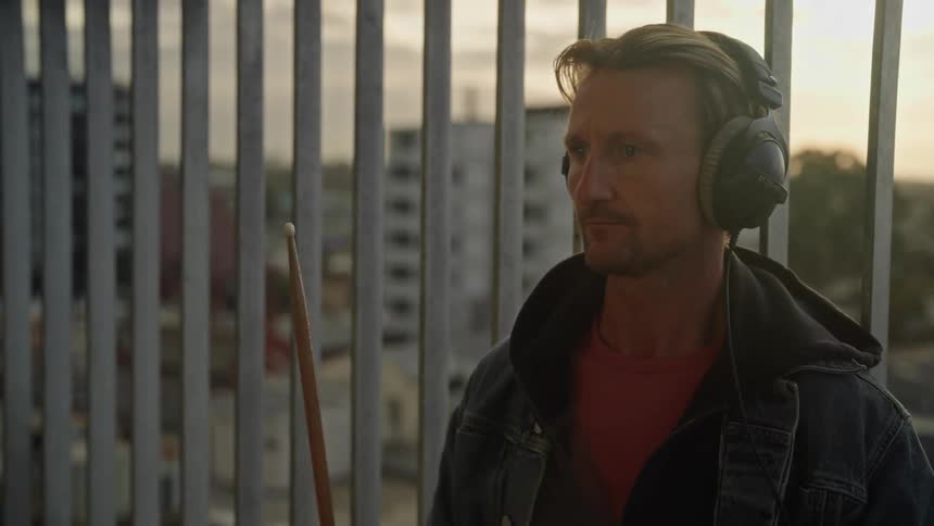 Man with headphones simulating playing drums with two drumsticks