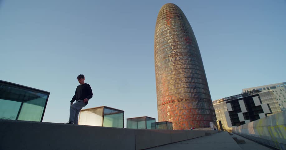 Young boy plays 'keep it up' with a soccer ball next to a modern building
