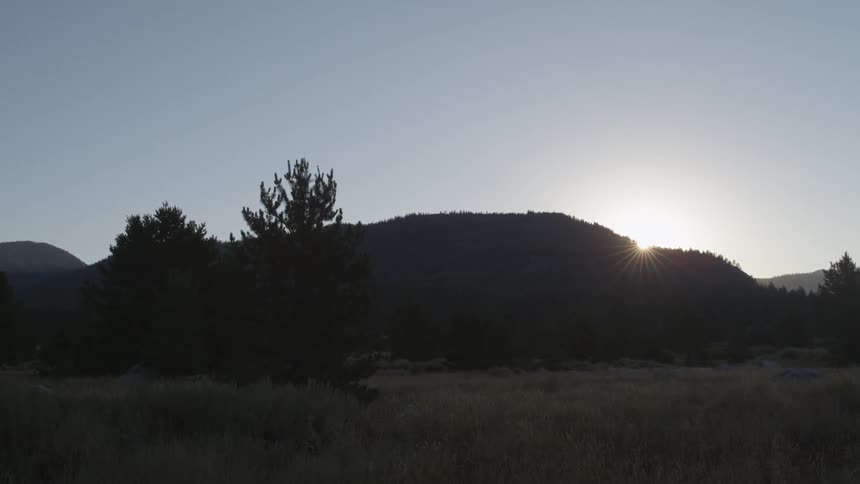 The sun is setting behind the hills ahead