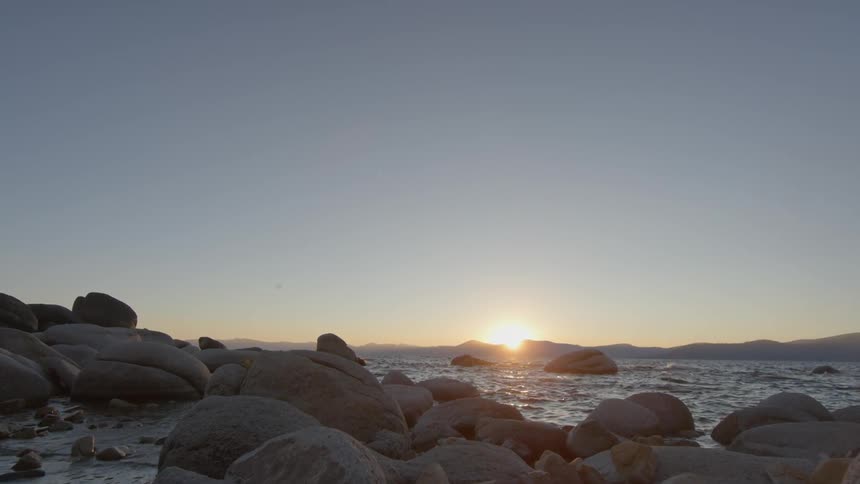 The sun is setting in the distance past the water
