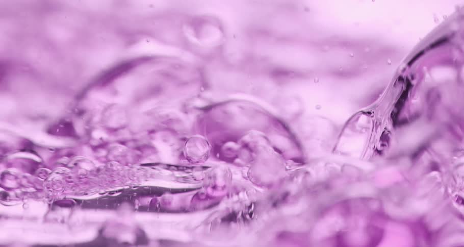 Bubbles float and move inside a clear lavender colored liquid