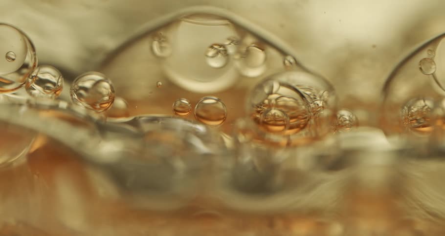 Orbs and bubbles float and move through a clear yellow liquid