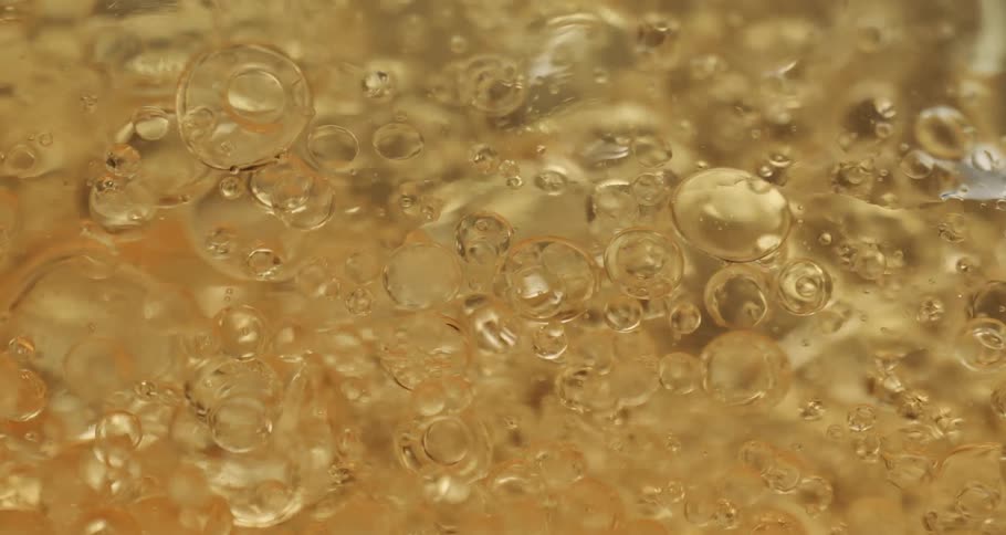 Bubbles float as they rise and move in a clear yellow liquid