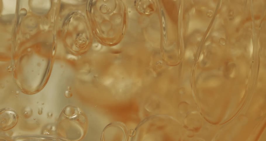 Air bubbles slowly move through a thick gold yellow liquid