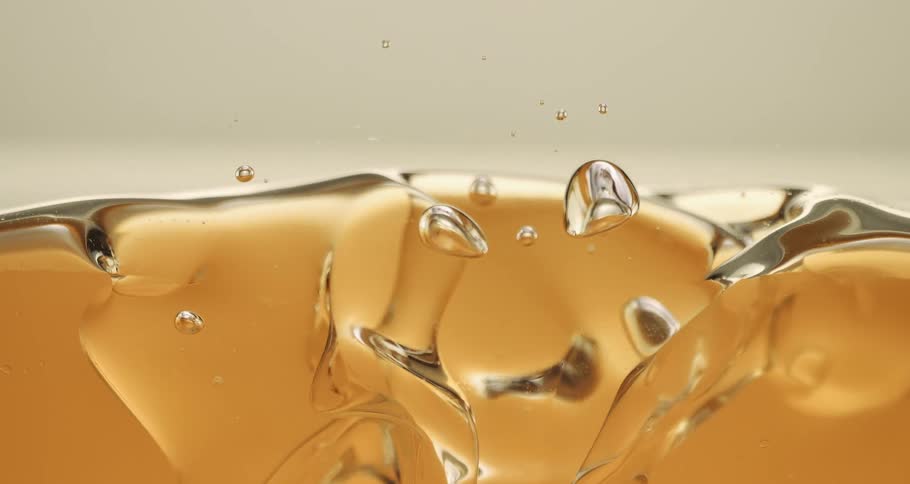 Clear water droplets fall into a tan opaque substance and mix with it