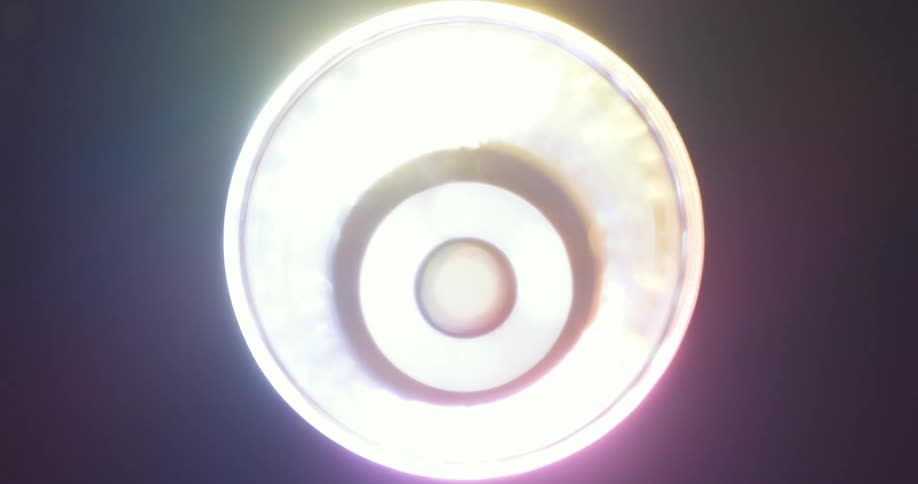 Colorful lights reflect and flare on a lens against a black background