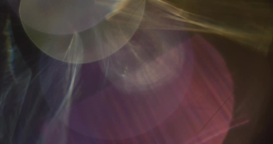 Colorful lights reflect and flare on a lens against a black background