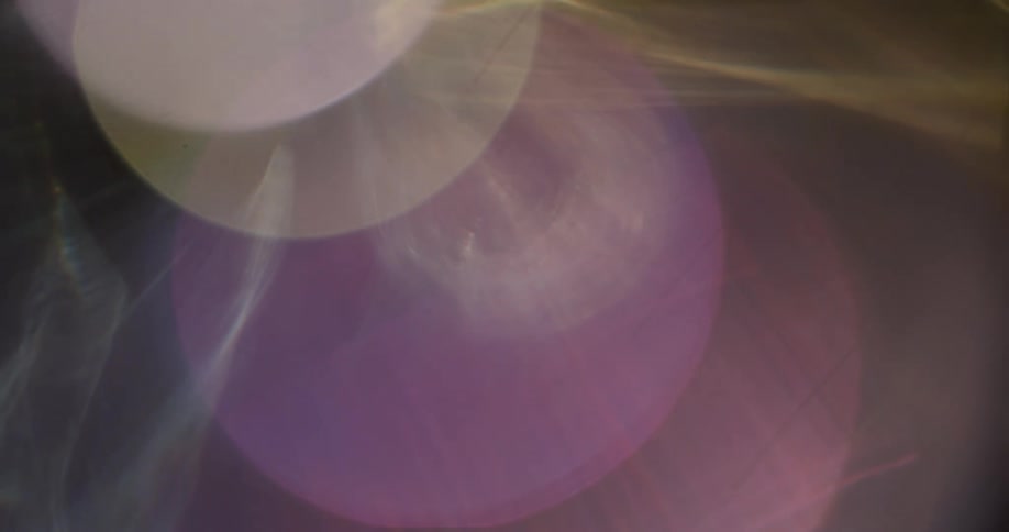 Light spots and rays in various colors float across solid background