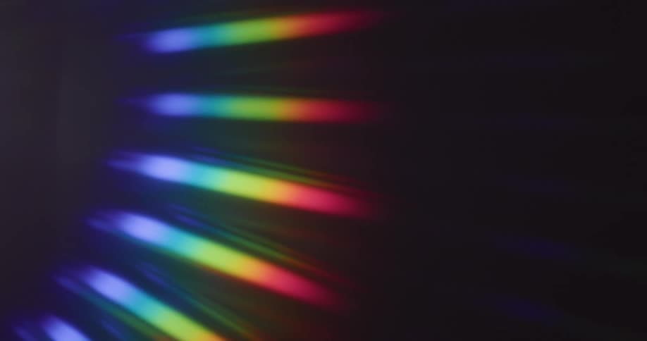 Rainbow colored beams of light rotating upward on a black background