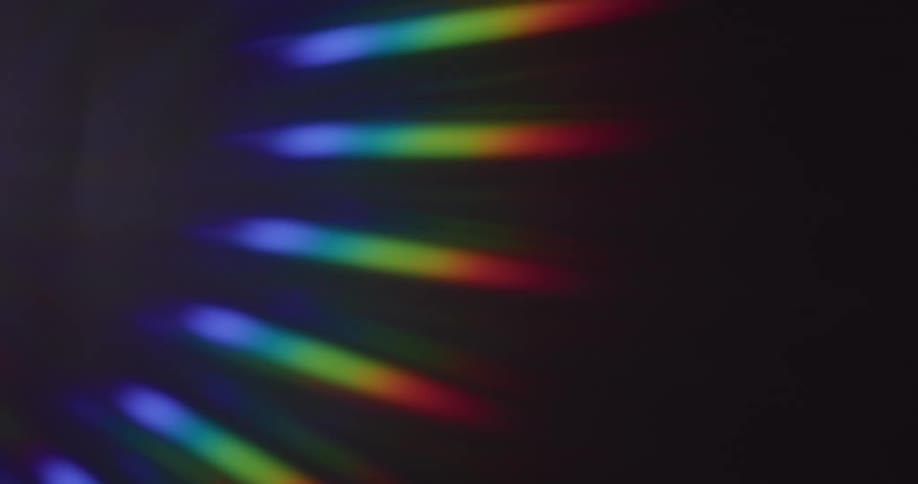 Glowing rainbow colored stripped bars of light shine in the darkness as they move