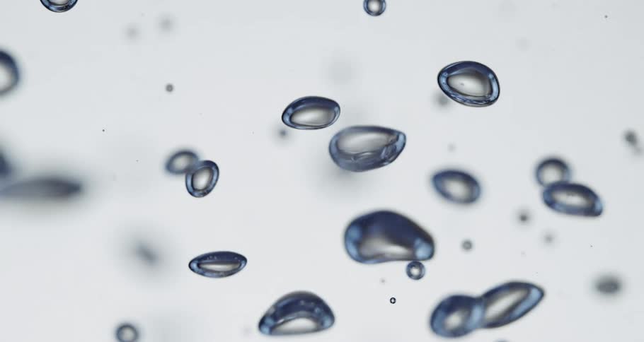 Bubbles with blue tinted surfaces float through a clear fluid