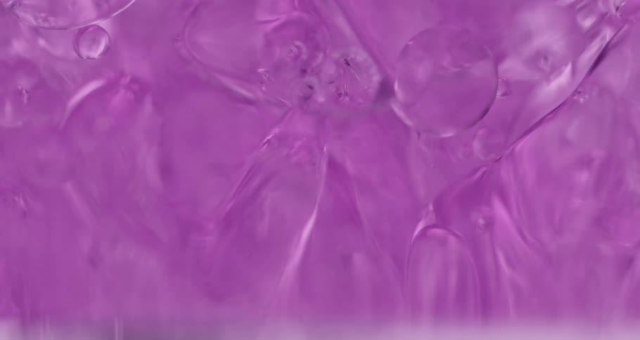 Air bubbles slowly move through a thick violet liquid