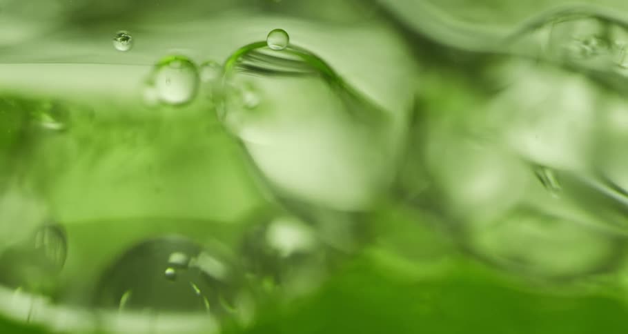 Air bubbles slowly move through a thick green liquid