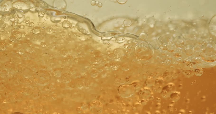 Clear soapy liquid bubbling up against a glass
