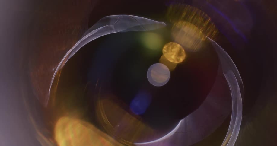 Colorful lights reflect and flare on a lens against a black background
