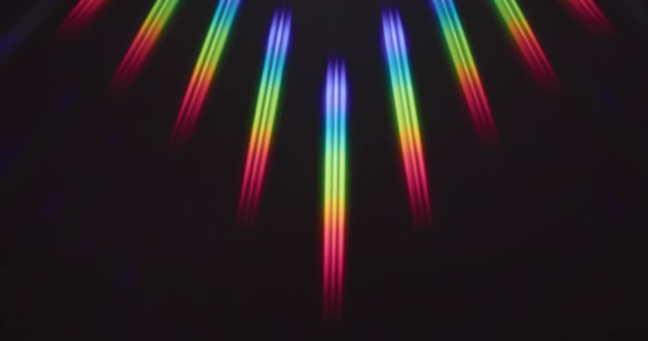 Rainbow rays of light spin on a black surface