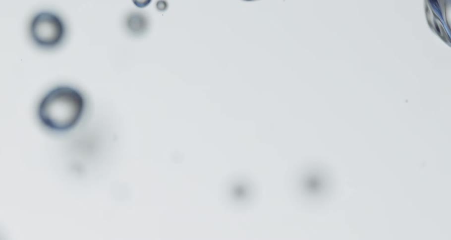 Water droplets moving around slowly on a white canvas background