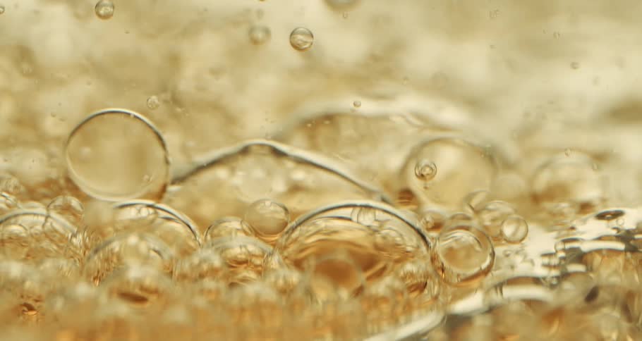 Orbs and bubbles float and move through a clear yellow liquid