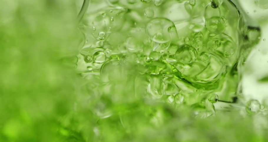 Orbs and bubbles float and move through a clear lime green liquid