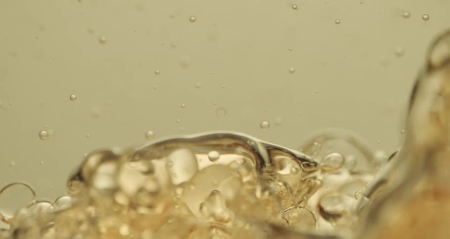 Air bubbles slowly move through a thick yellow liquid