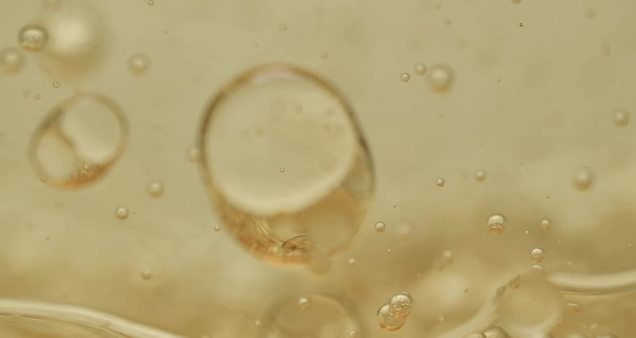 Orbs and bubbles float and move through a clear yellow liquid