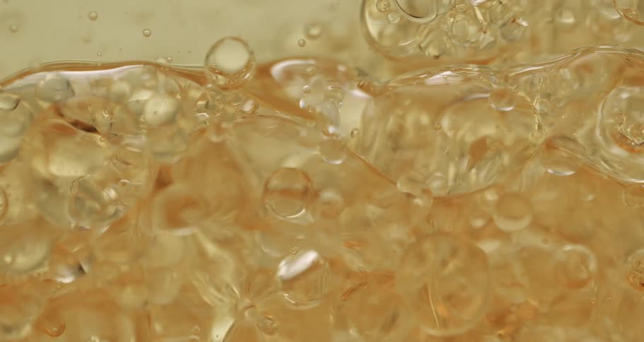 Orbs and bubbles float and move through a clear yellow liquid