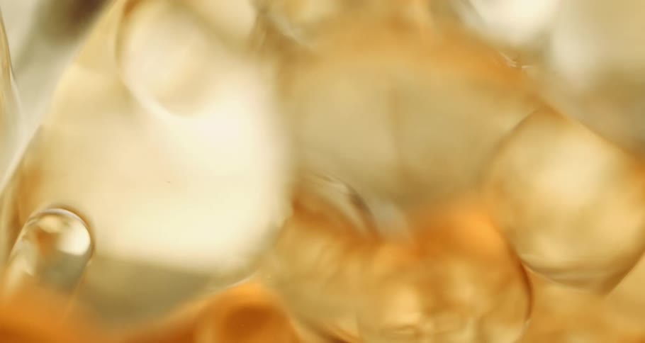 Bubbles and ice bob through amber beverage in glass