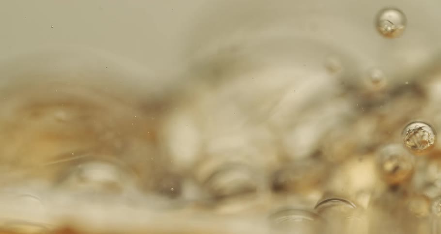 Air bubbles slowly move through a thick yellow liquid
