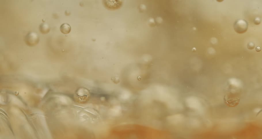 Air bubbles slowly move through a thick yellow liquid