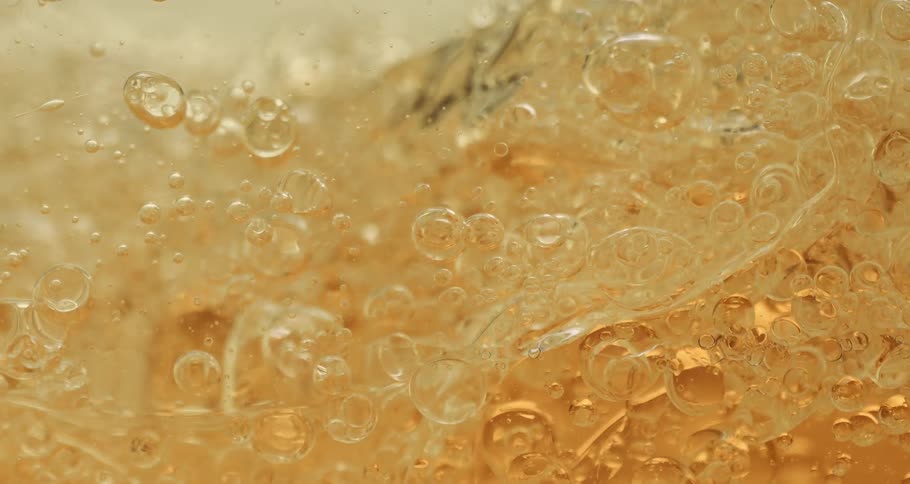 The bubbles float in the gold liquid
