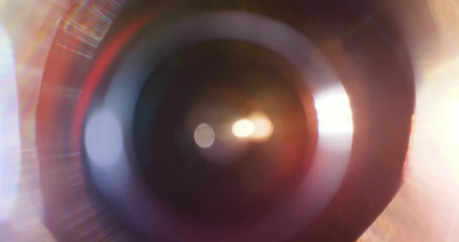 Colorful lights reflect and flare on a lens against a black background