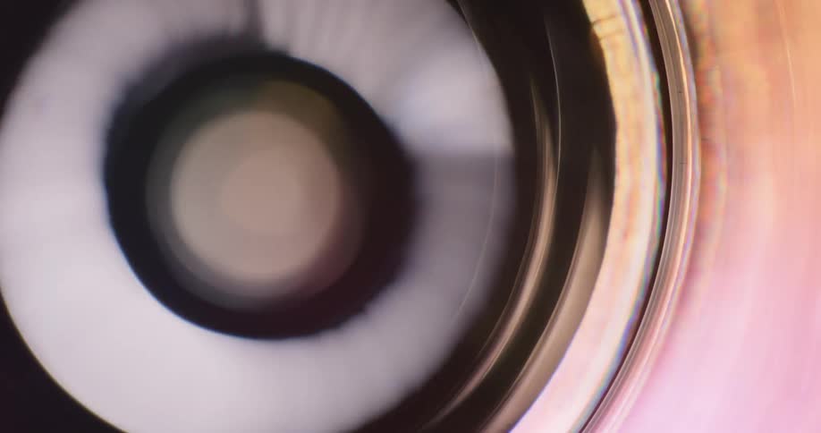 Colorful lights reflect and flare on a lens against a black background
